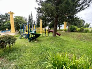 a playground in a grassy field with a tree at Tagaytay Sweet Home in Tagaytay