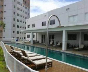 a swimming pool with lounge chairs next to a building at Lar de piatã 2 quartos in Salvador