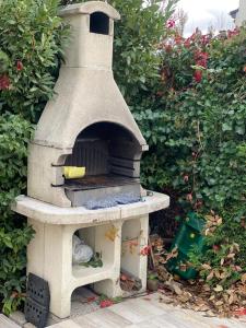 a outdoor oven sitting in front of a bush at Villa Houria in Gonesse