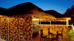 a restaurant with a straw roof with chairs and a bar at The MadhuNandan in Rāmnagar