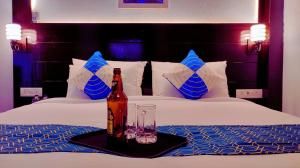 a bottle of beer and glasses on a bed at The MadhuNandan in Rāmnagar +42 photos