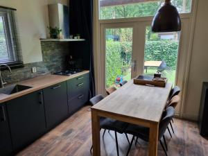 cocina con mesa de madera y algunas sillas en Vakantiehuis Veluws Genieten met whirlpool en sauna, en Doornspijk