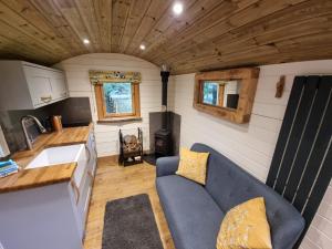 ein Wohnzimmer mit blauer Couch in einem winzigen Haus in der Unterkunft Syke Farm Campsite - Yurt's and Shepherds Hut in Buttermere