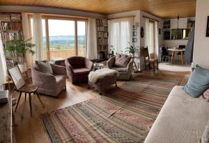 a living room with a couch and chairs and a large window at Wohlfühl-Haus mit Panoramablick in Oberneuforn