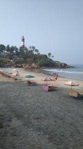 a group of tables and umbrellas on a beach at Sky Palace Beach Hotel in Trivandrum