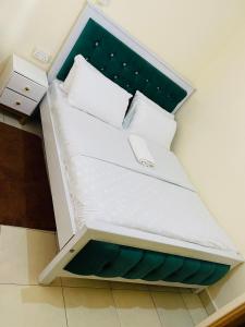 a small bed with a green headboard and white pillows at Homes by Essyruby in Nairobi