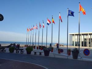 un montón de banderas frente a una playa en Le Cocon de Neptune en Arromanches-les-Bains