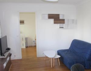 a living room with a blue couch and a table at Au Tour Des Bois in Le Vésinet