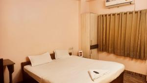um quarto com uma cama com lençóis brancos e uma janela em hotel darbar international em Gaya