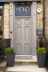 eine graue Tür eines Gebäudes mit zwei Pflanzen davor in der Unterkunft MONO Suites NEW TOWN in Edinburgh