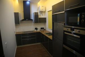 cocina con armarios negros y nevera negra en Gulberg Suites, en Lahore