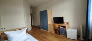 a bedroom with a bed and a desk with a television at HW Hotel - Haus am Niederfeld in Berlin