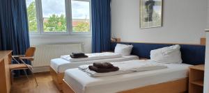 2 Betten in einem Hotelzimmer mit Handtüchern darauf in der Unterkunft HW Hotel - Haus am Niederfeld in Berlin
