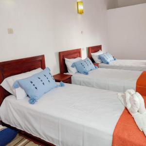 3 Betten in einem Zimmer mit blauen und weißen Kissen in der Unterkunft Riad bounaylat 