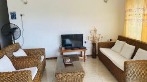 a living room with wicker furniture and a tv at HORIZON selfcatering in Beau Vallon