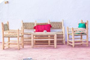a wooden table with two chairs and a table with a red pillow at Riad bounaylat in Toug er Rih
