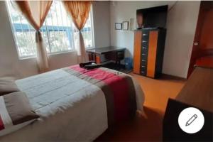 een slaapkamer met een groot bed en een televisie bij Semirita in Azogues