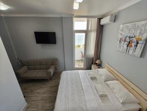 1 dormitorio con cama, sofá y TV en Queen Tamara Apartments, en Makhinjauri