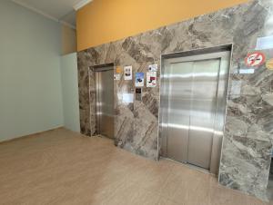 un vestíbulo con 2 ascensores y una pared de piedra en Queen Tamara Apartments, en Makhinjauri