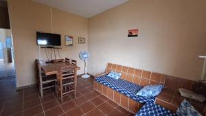 a room with a couch and a desk and a television at Temporada no Paraíso in Ilha Comprida