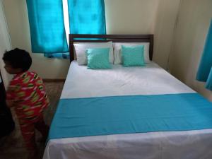 a little boy standing next to a bed in a room at Island Breeze in Mahébourg