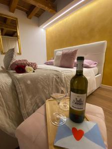 uma garrafa de vinho numa mesa ao lado de uma cama em The Key Of Bergamo em Bérgamo