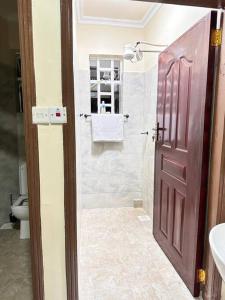La salle de bains est pourvue d'une douche et d'une porte marron. dans l'établissement Luxurious 2 bedroom penthouse-Fully Furnished, à Kitale