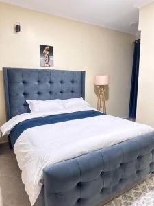 Luxurious 2 bedroom penthouse-Fully Furnished في كيتالي: سرير كبير مع اللوح الأمامي الأزرق في غرفة النوم