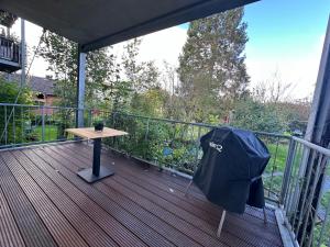 una terraza de madera con una mesa y una sombrilla. en Apartment in Bad Wilhelmshöhe mit großem Balkon im Grünen und kostenfreien Parkplätzen, en Kassel