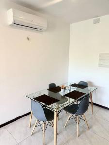 une table en verre avec quatre chaises dans une pièce dans l'établissement Hermoso apartamento en Asuncion, à Asuncion