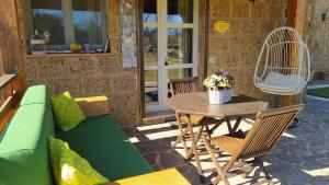 un patio con un sofá verde, una mesa y sillas en Agriturismo La Dependance en Sorano