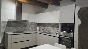 a kitchen with white cabinets and a stove top oven at Alloggio turistico Pietra Viva in Vitorchiano