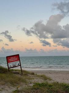 a sign on the beach with the ocean in the background at Casa Amarela, para veraneio em Areia Dourada in Cabedelo