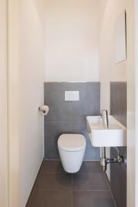 een badkamer met een wit toilet en een wastafel bij POHA House Theaterplatz in Aken