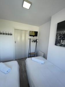 Duas camas num quarto com paredes brancas em Apartamento Ski Place 6 personas em Serra Nevada