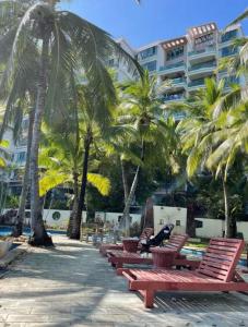 a row of red benches with palm trees and a building at Sunny Apartment, minutes to beach in Shuijiao