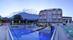 ケメルにあるErkal Resort Hotelの山を背景にスイミングプールを併設するホテル
