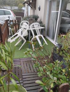 2 chaises blanches assises sur la terrasse couverte avant d'une maison dans l'établissement Launay, à Chènehutte-les-Tuffeaux