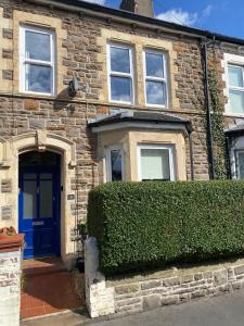 ceglany dom z niebieskimi drzwiami i żywopłotem w obiekcie Cardiff - Home from Home w Cardiff