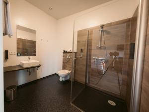 a bathroom with a shower and a toilet and a sink at Hotel Vos in Hella