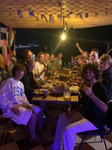 een groep mensen die 's nachts rond een tafel zitten bij sunny wave taghazout SURF & YOGA in Taghazout