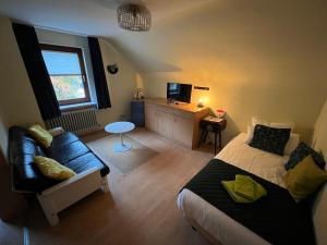 a bedroom with a bed and a couch and a table at Am Obersee Hotel in Simmerath