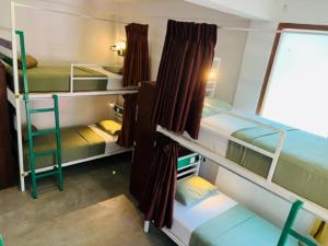 a room with three bunk beds and a window at Downtown Hostel Ella in Ella