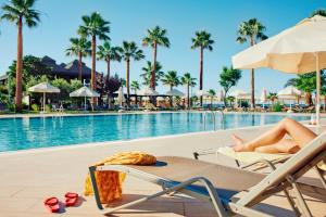 a woman laying on a lounge chair next to a swimming pool at TUI MAGIC LIFE Masmavi in Belek