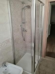 Una ducha con puerta de cristal junto al lavabo en Casa vacanza Lara, en Santa Brigida
