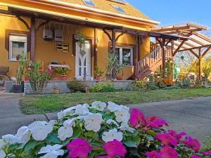 een geel huis met bloemen ervoor bij Holt-Tisza Vendégház in Szeged