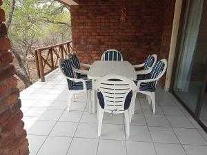 - une table et des chaises blanches sur la terrasse dans l'établissement Le Lion Dort, à Marloth Park