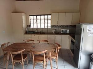a kitchen with a wooden table and chairs and a refrigerator at Le Lion Dort in Marloth Park