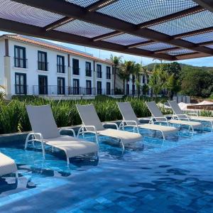 a row of lounge chairs on a swimming pool at Flat da Mata - Resort Quinta Santa Bárbara in Pirenópolis