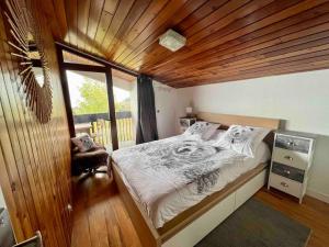 Chalet spacieux et convivial LA TOUSSUIRE في لا توسوير: غرفة نوم بسرير كبير بسقف خشبي